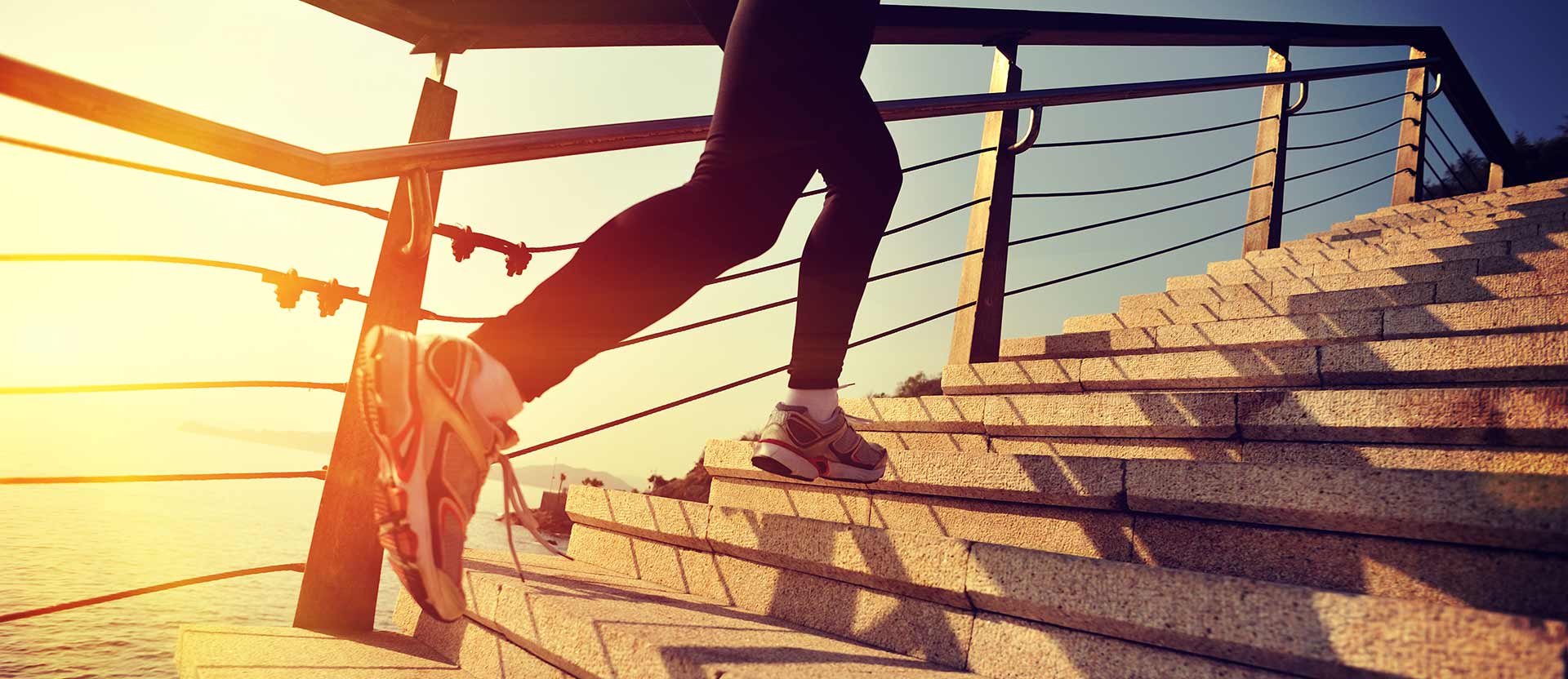 This is an image of a person in athletic clothing running up a flight of stairs outdoors.