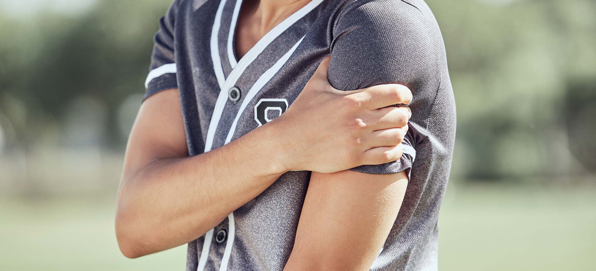 This is an image of a young athletic man holding his left shoulder, indicating left shoulder pain or injury.