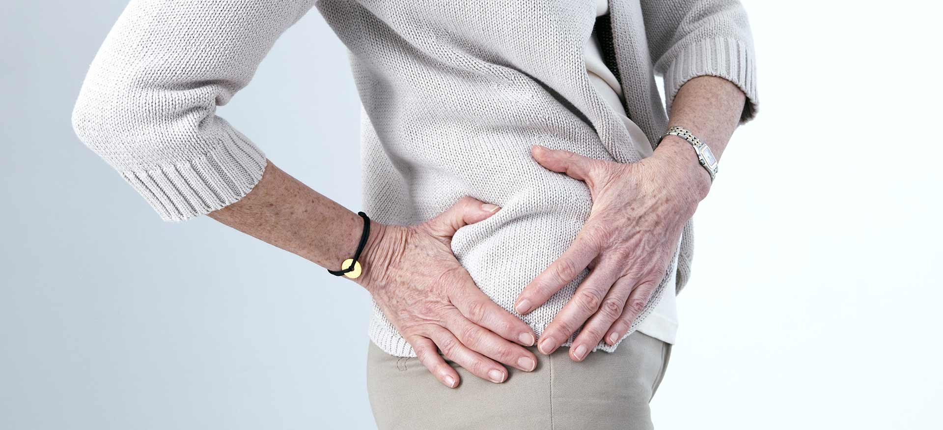 This is an image of an older woman holding her right hip, indicating right hip pain or injury.