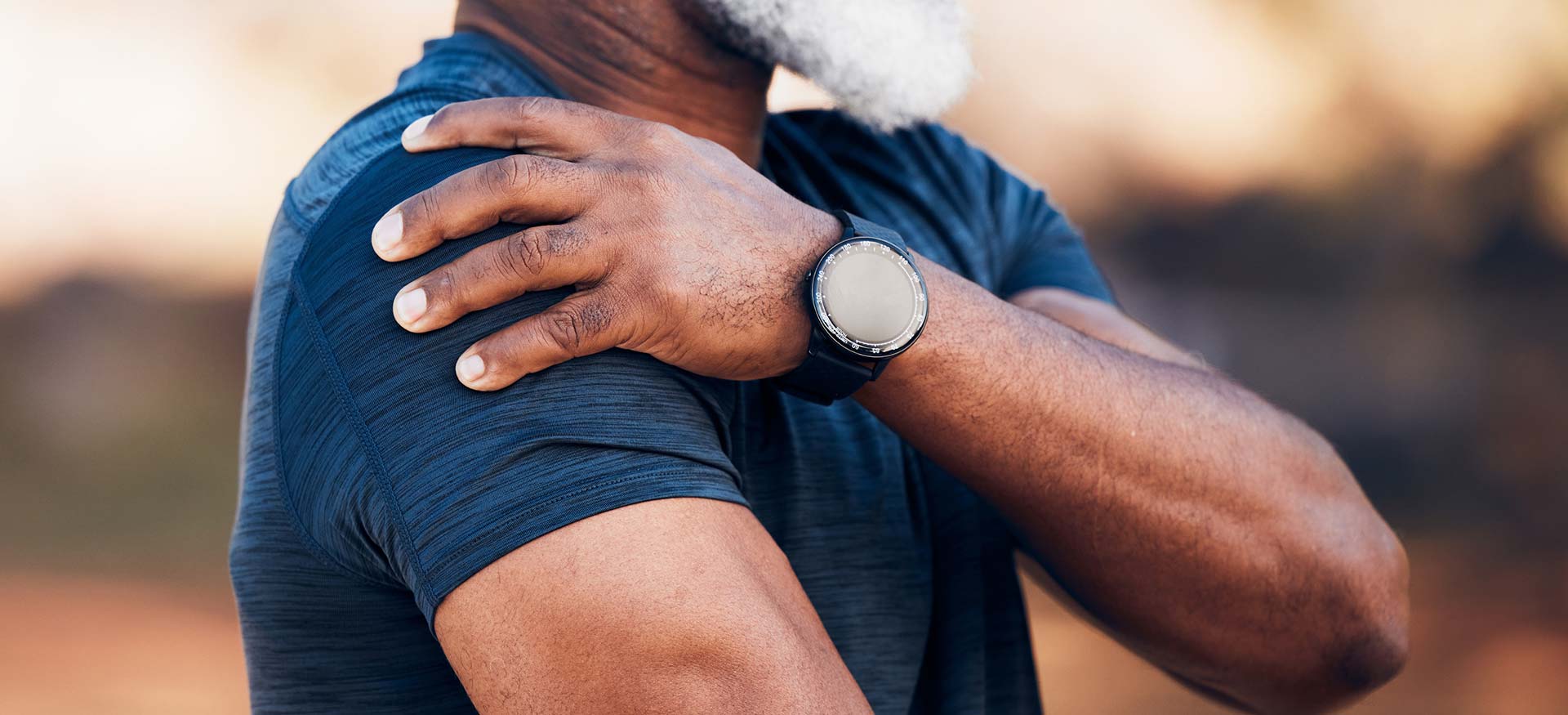 This is an image of an athletic older man holding his right shoulder, indicating shoulder pain or injury.